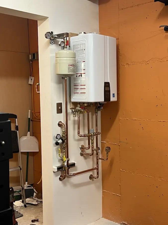 Plumbing technician inspecting water heater connections in Glennville